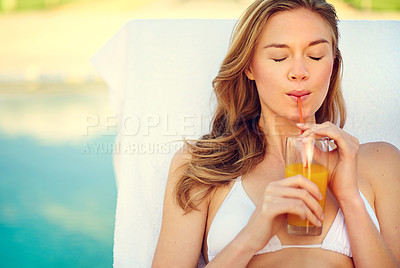 Buy stock photo Shot of an attractive young woman enjoying a poolside drink