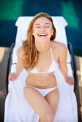 Buy stock photo Shot of a young woman relaxing on a lounge chair beside a swimming pool