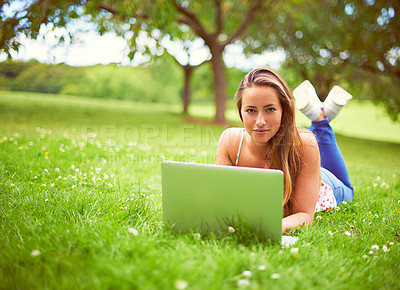 Buy stock photo Shot of a young woman using her laptop at the park