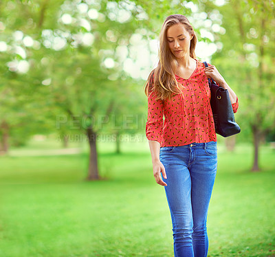 Buy stock photo Shot of a young woman walking in a park