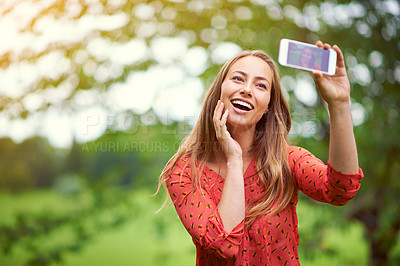 Buy stock photo Shot of a young woman taking a selfie outside