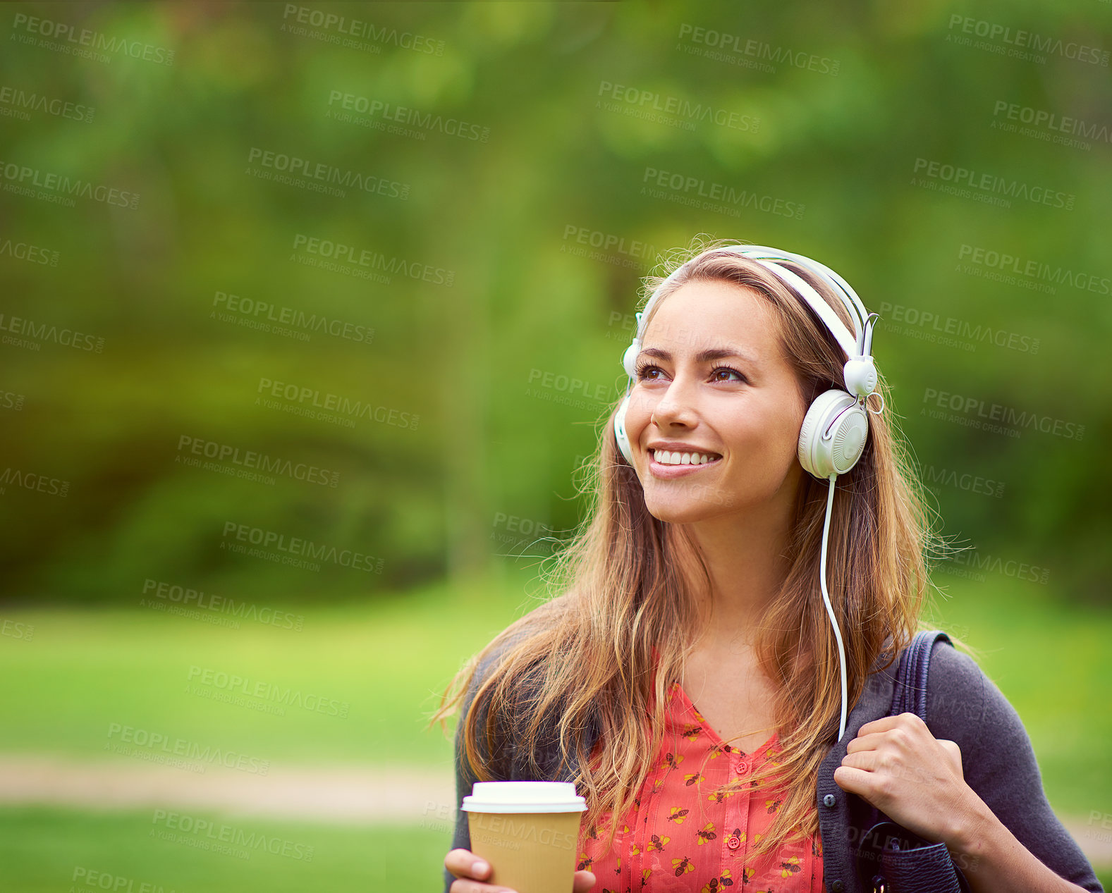 Buy stock photo Shot of a young woman listening to music while having a coffee on the go