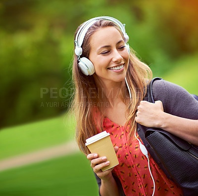 Buy stock photo Shot of a young woman listening to music while having a coffee on the go