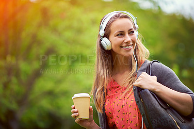Buy stock photo Shot of a young woman listening to music while having a coffee on the go