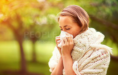 Buy stock photo Shot of a young woman blowing her nose outside