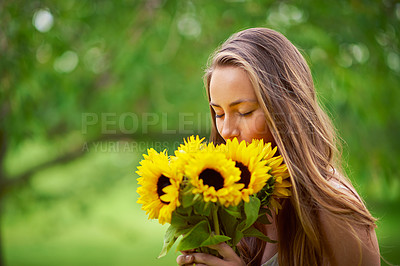 Buy stock photo Shot of a young woman holding a bunch of sunflowers outside