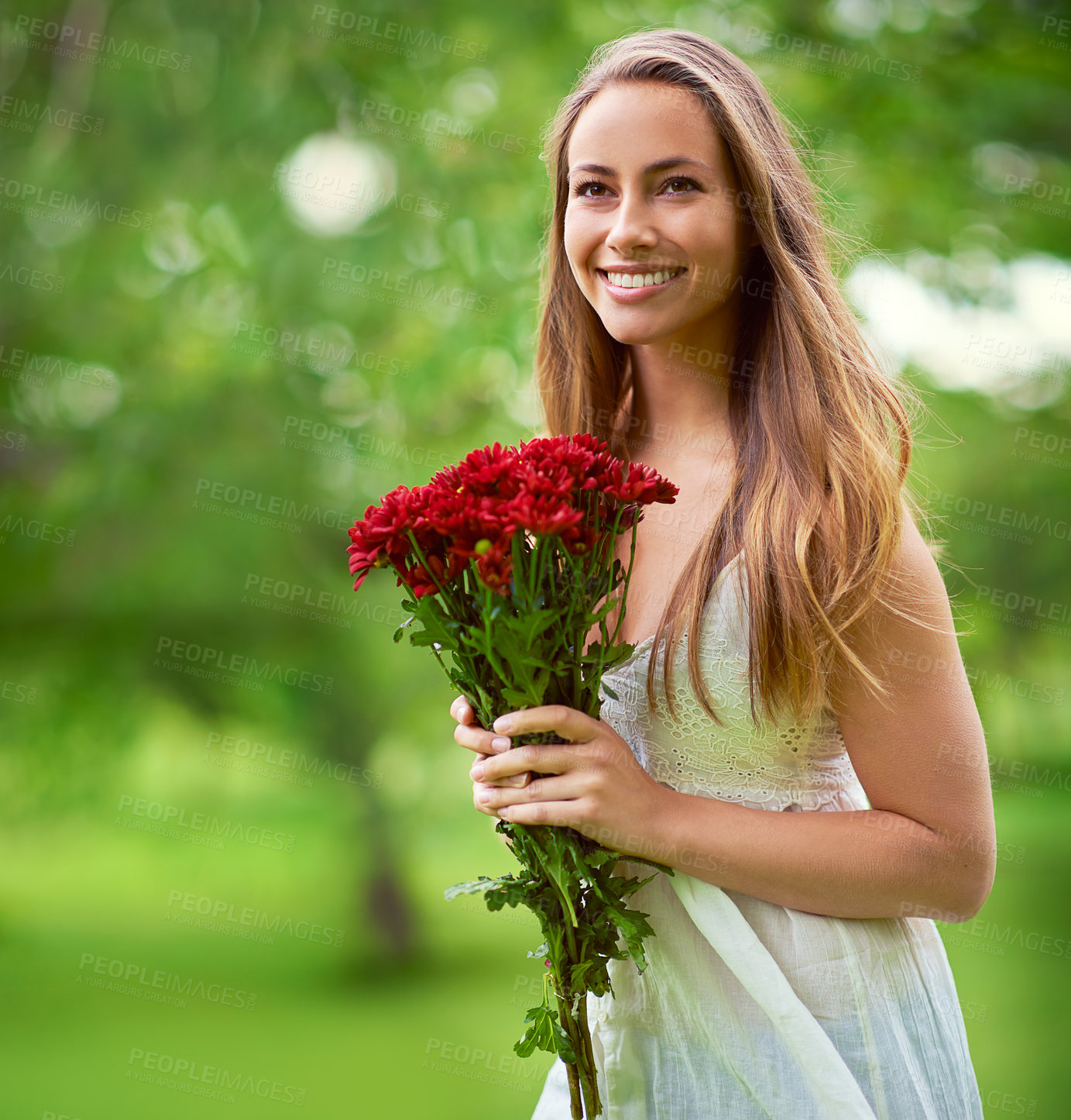 Buy stock photo Shot of a young woman holding a bunch of red flowers outside