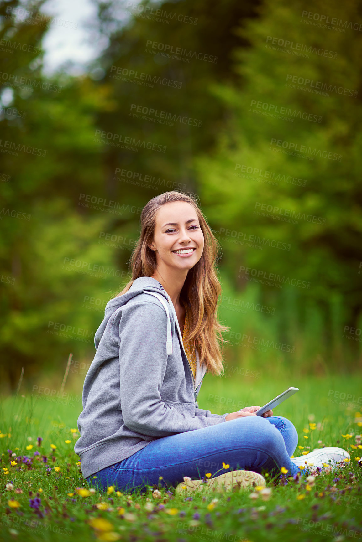 Buy stock photo Shot of a young woman using her digital tablet at the park