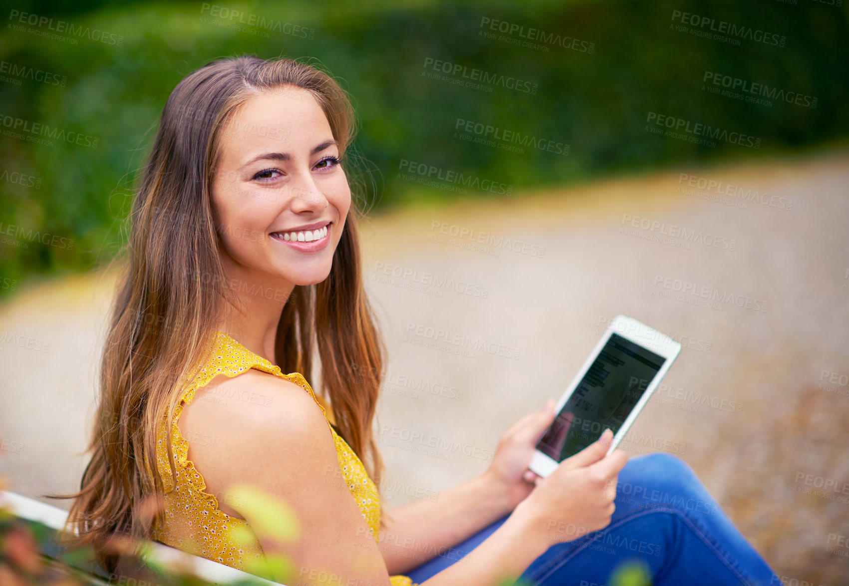 Buy stock photo Shot of a young woman using a digital tablet at the park