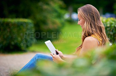 Buy stock photo Shot of a young woman using a digital tablet at the park