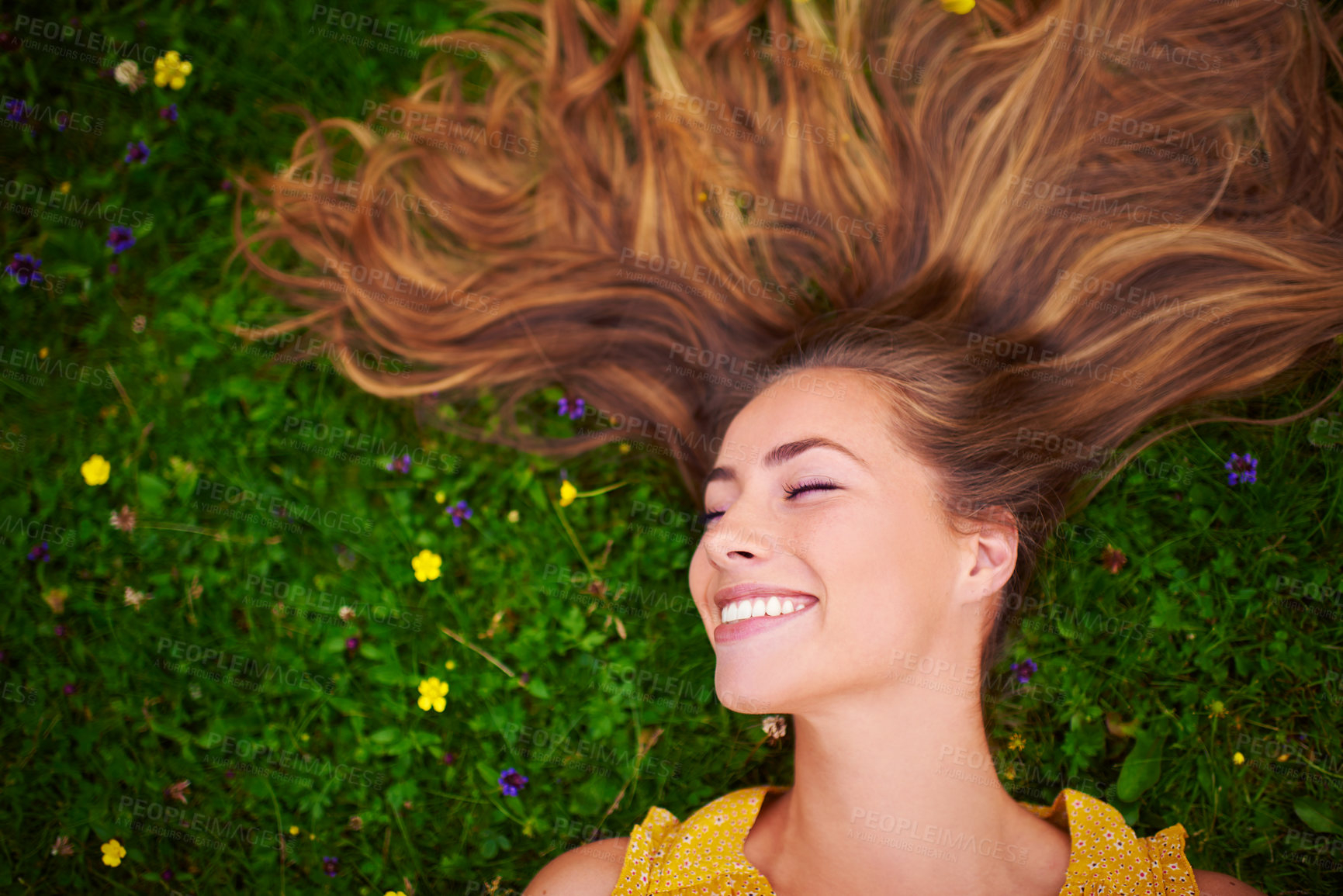 Buy stock photo High angle shot of a carefree young woman relaxing in a field of grass and flowers