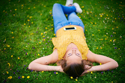 Buy stock photo Shot of a young woman lying down in a field of grass