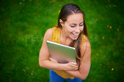 Buy stock photo Shot of a happy young woman holding a laptop in the park