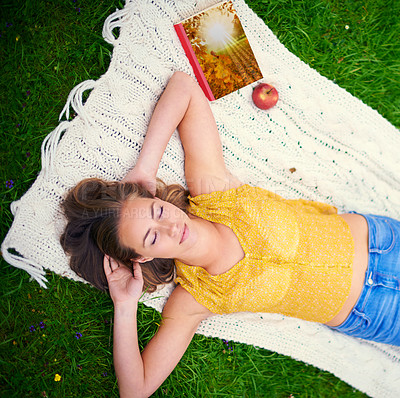 Buy stock photo Shot of a carefree young woman relaxing on a blanket in the park