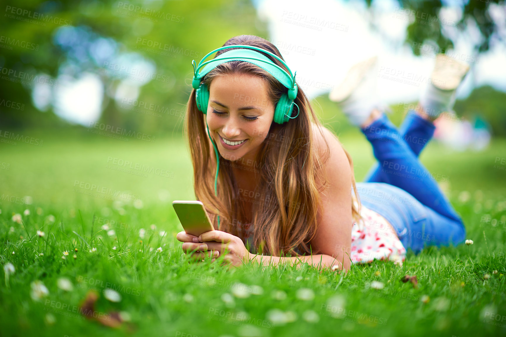 Buy stock photo Woman, phone and happy on grass with headphones, lying and listen to music, memory and thinking in spring. Girl, student and reflection with smartphone at campus for streaming subscription on web