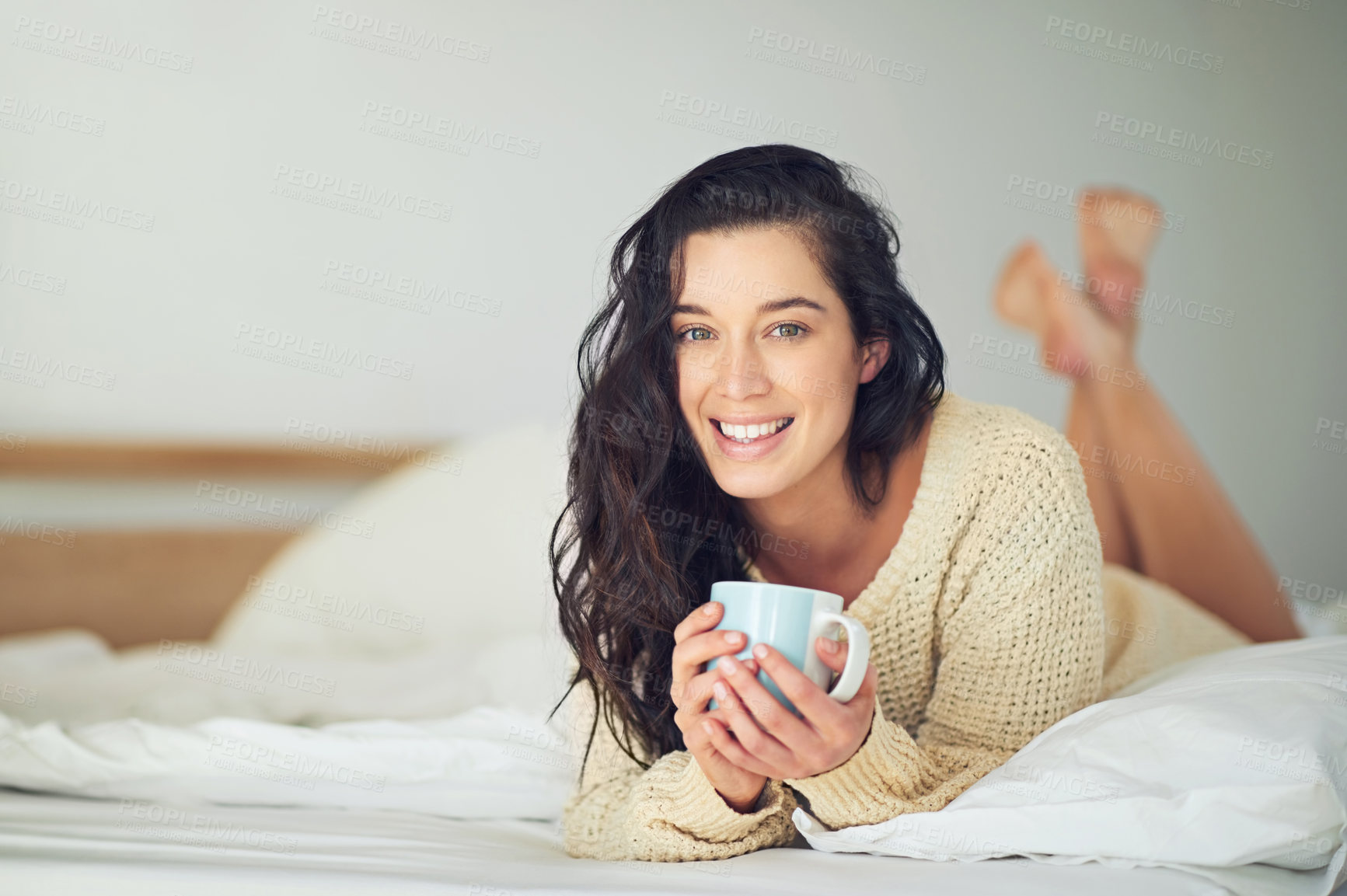 Buy stock photo Full length portrait of a young woman drinking coffee while lying on her bed