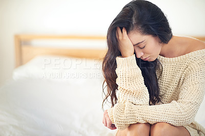 Buy stock photo Cropped shot of a young woman looking dejected while sitting on the edge of her bed