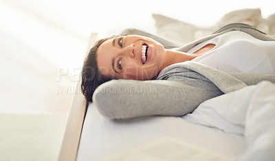 Buy stock photo Cropped shot of a young woman laughing while lying on her bed