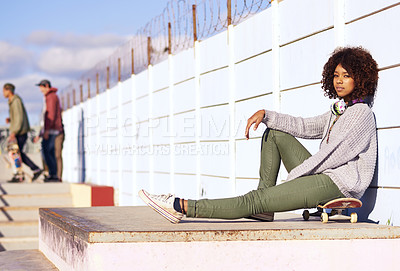 Buy stock photo Portrait, serious and woman with skateboard in city by wall in summer for sport, fashion or relax outdoor. Young person, skate park and gen z girl in casual clothes with headphones in South Africa