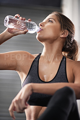 Buy stock photo Cropped shot of a young woman drinking from her water bottle at the gym