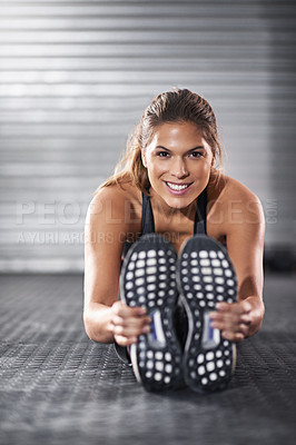 Buy stock photo Shot of a young woman stretching her legs before a gym workout