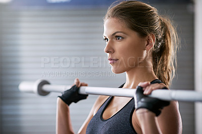 Buy stock photo Shot of a young woman working out with a barbell at the gym