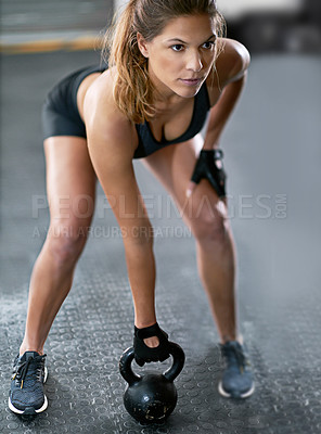 Buy stock photo Shot of a young woman working out with a kettle bell at the gym