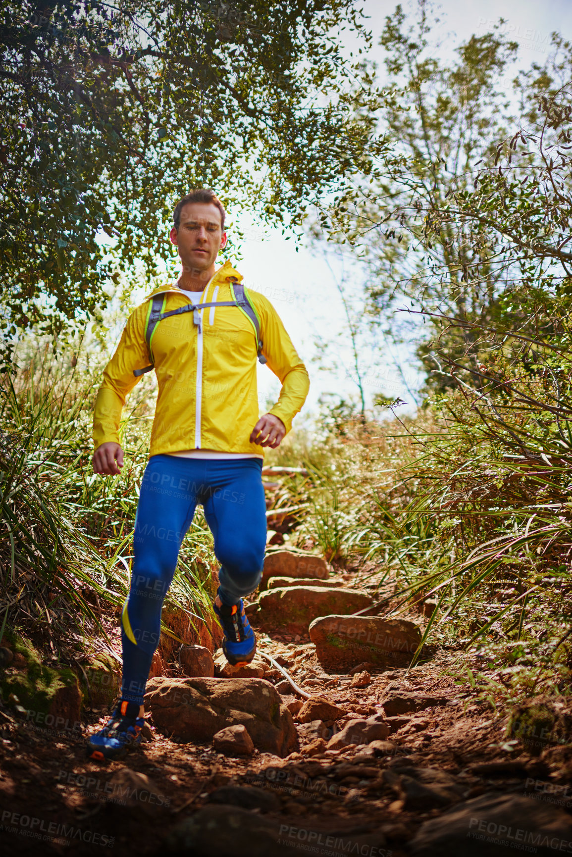 Buy stock photo Shot of a young man running along a nature trail