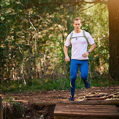 Buy stock photo Shot of a young man running along a nature trail