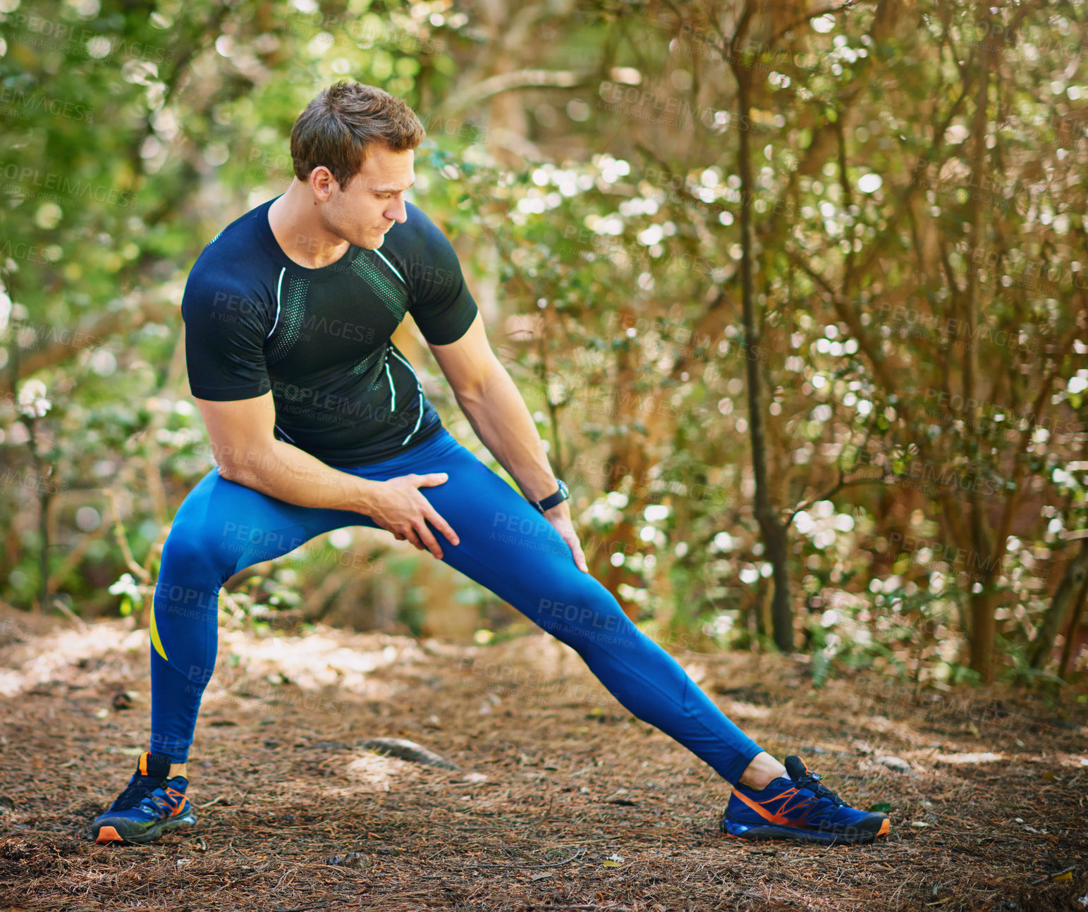Buy stock photo Shot of a young man stretching before a trail run