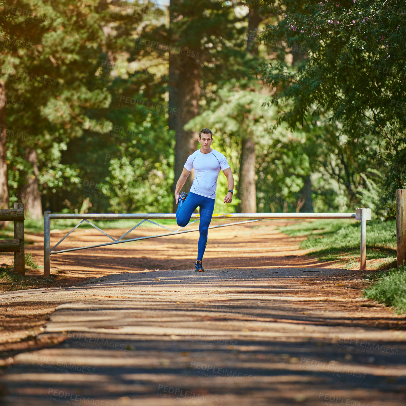 Buy stock photo Shot of a young man stretching before a trail run