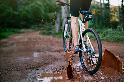 Buy stock photo Cropped shot of a male cyclist riding along a muddy mountain bike trail