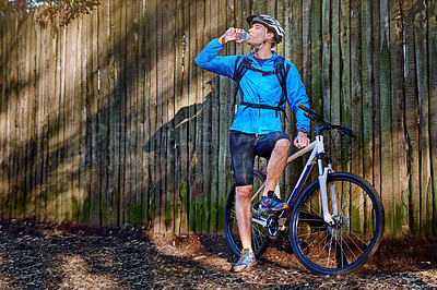 Buy stock photo Shot of a male cyclist stopping for a water break while out for a ride on his mountain bike
