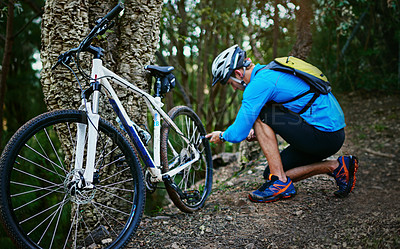 Buy stock photo Shot of a cyclist inflating the tires of his mountain bike while out for a ride