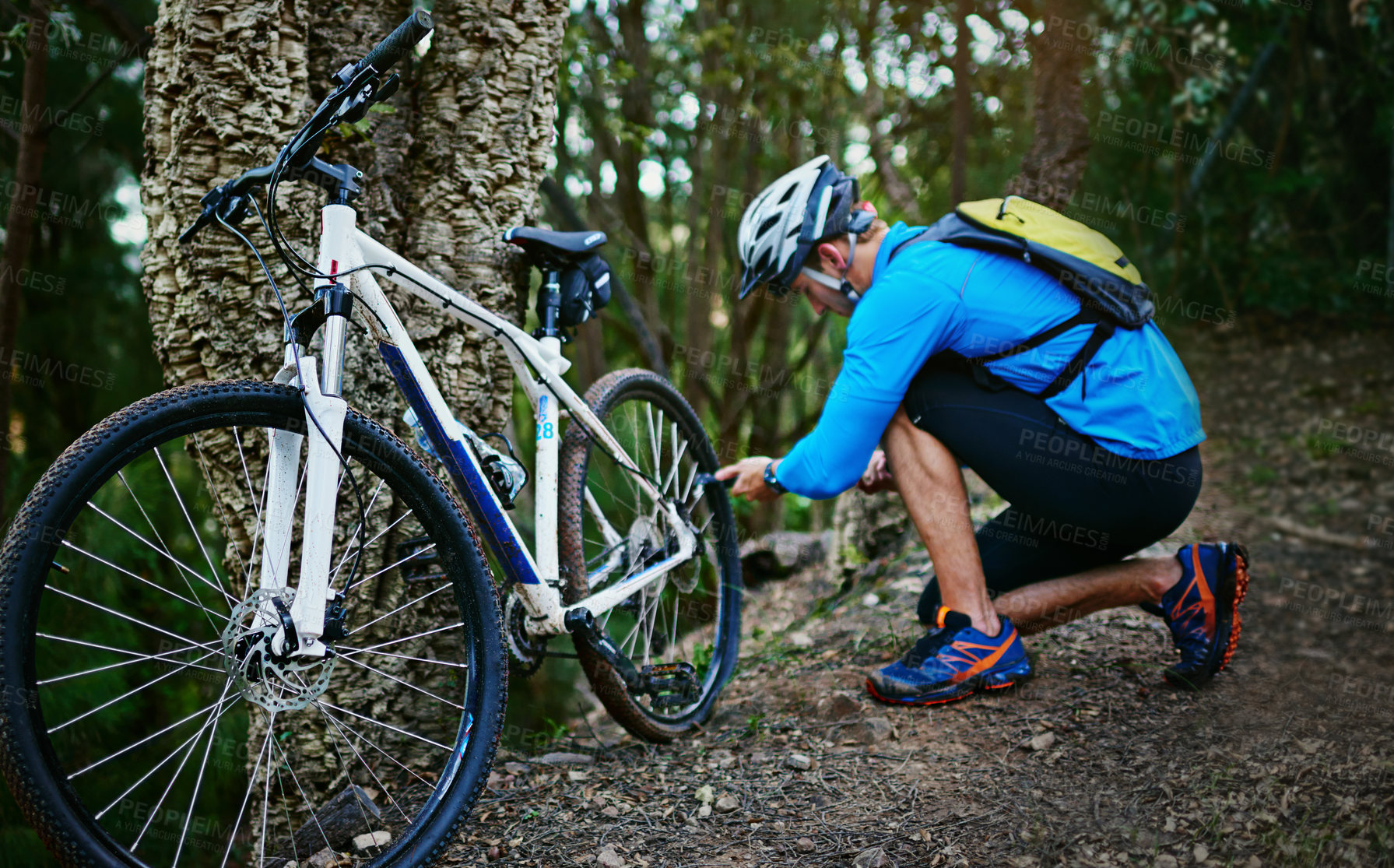 Buy stock photo Shot of a cyclist inflating the tires of his mountain bike while out for a ride