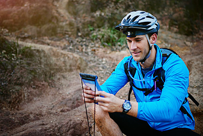 Buy stock photo Shot of a cyclist using his smartphone while out for a ride