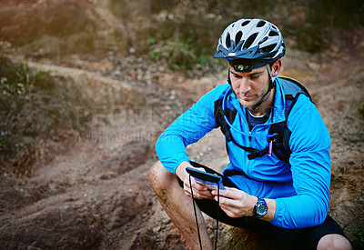 Buy stock photo Shot of a cyclist using his smartphone while out for a ride