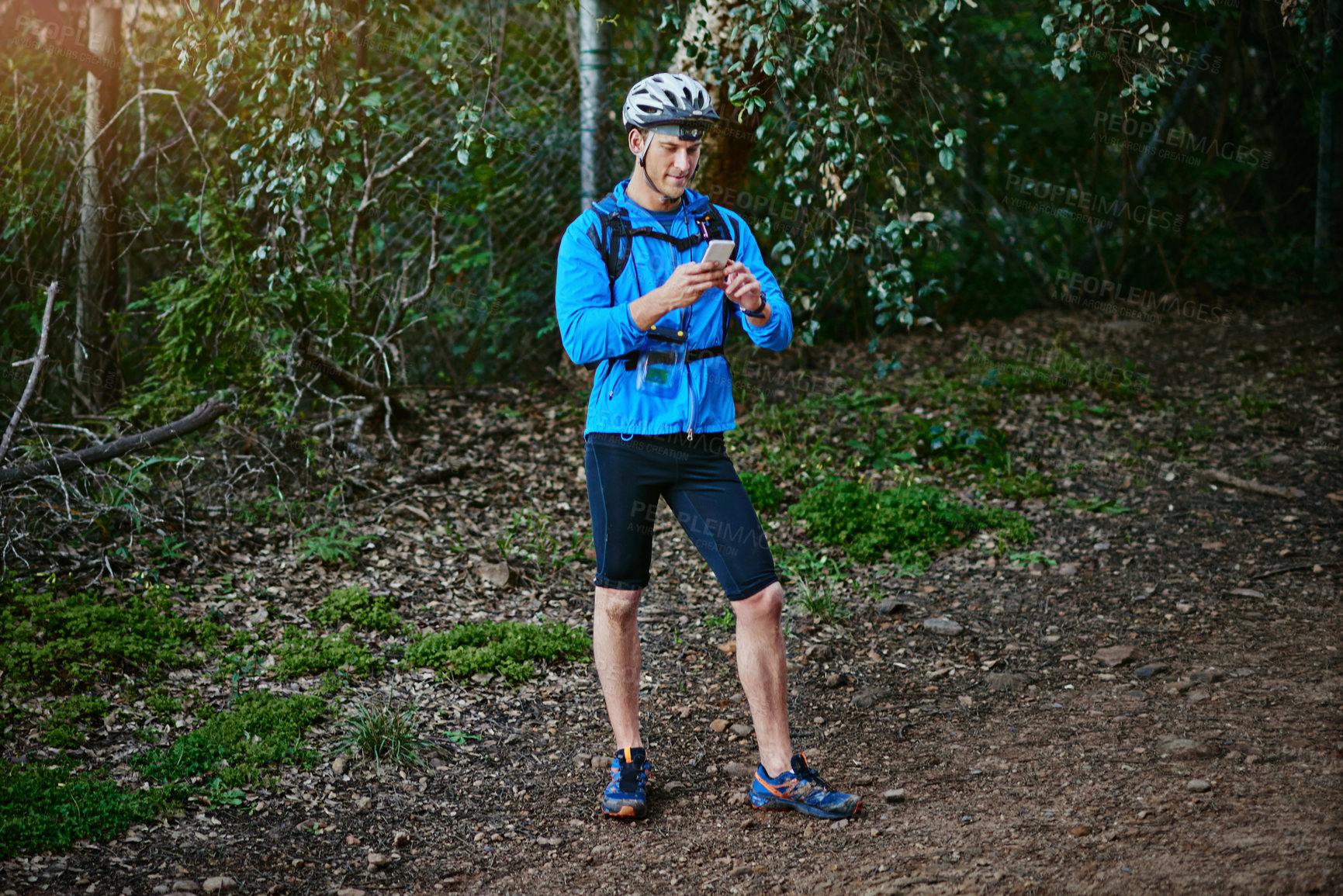 Buy stock photo Shot of a cyclist using his smartphone while out for a ride