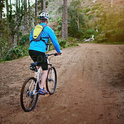 Buy stock photo Shot of a male cyclist riding along a mountain bike trail