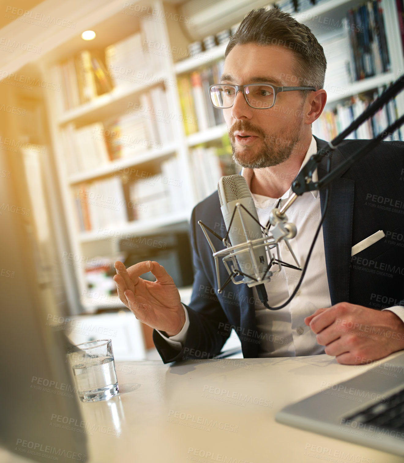 Buy stock photo Shot of a businessman making a podcast on his computer