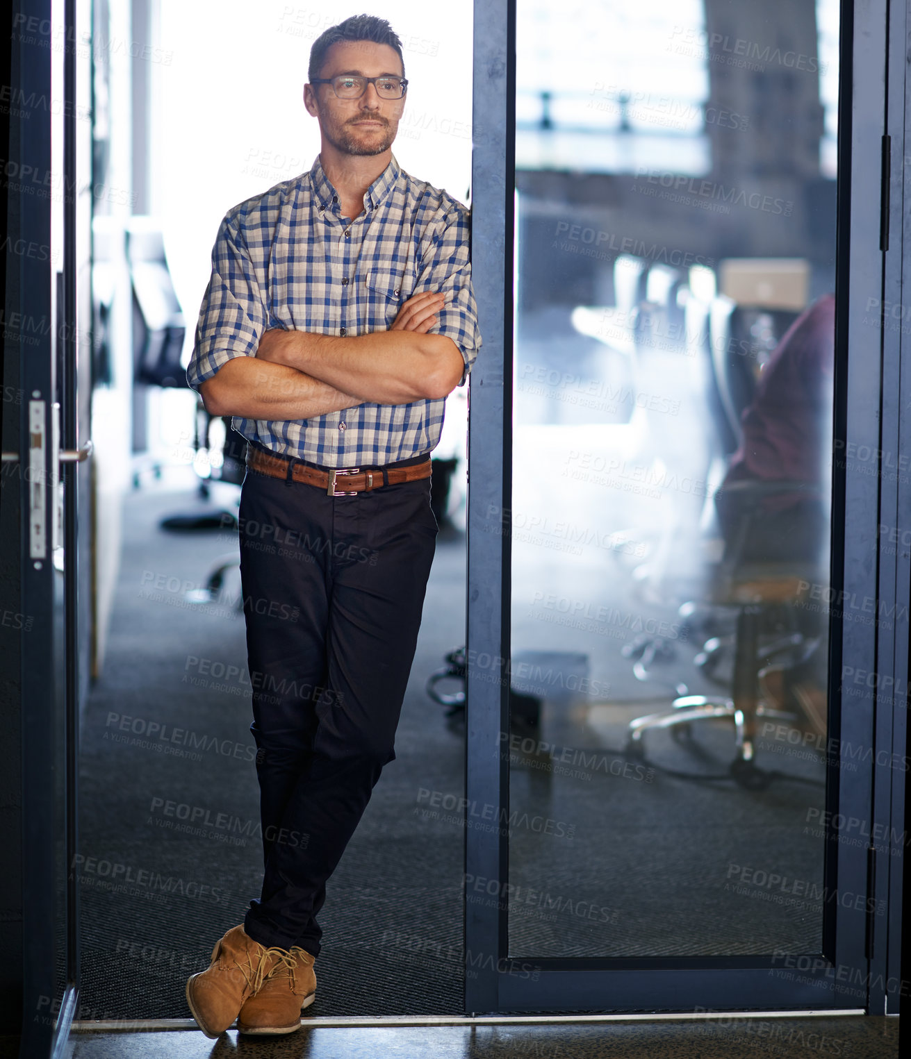 Buy stock photo Shot of an office worker looking thoughtful while leaning against a glass door