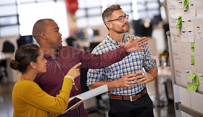 Buy stock photo Shot of a group of coworkers brainstorming at a whiteboard