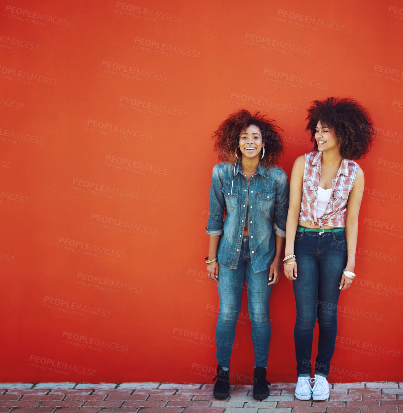 Buy stock photo Shot of two young friends posing in front of a red wall