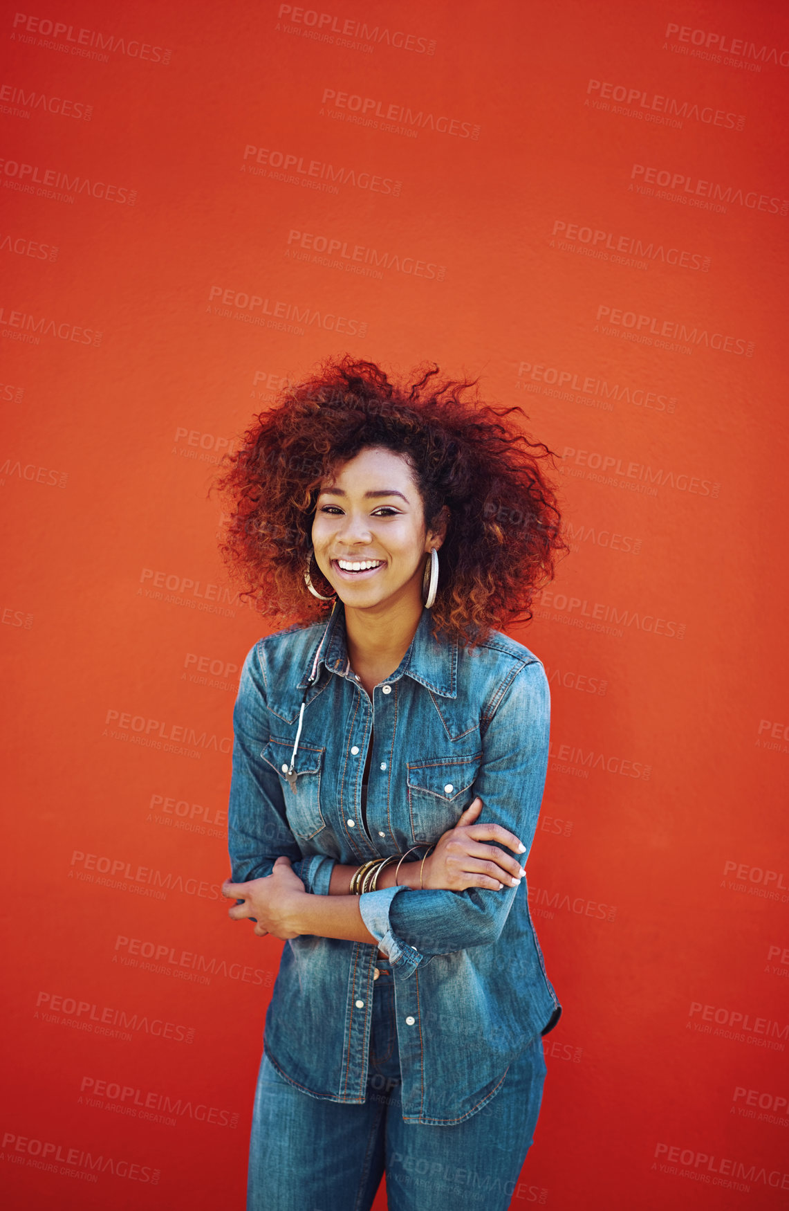 Buy stock photo Woman, portrait and happy in fashion by wall with casual style, trendy outfit and denim clothes on red background. Girl, person and confidence in city with streetwear, afro or pride with mockup space