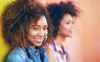 Buy stock photo Portrait of an attractive young woman posing with her friend against a colorful wall