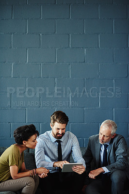 Buy stock photo Shot of a group of coworkers working together with a digital tablet
