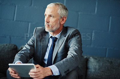Buy stock photo Shot of a thoughtful businessman using a digital tablet
