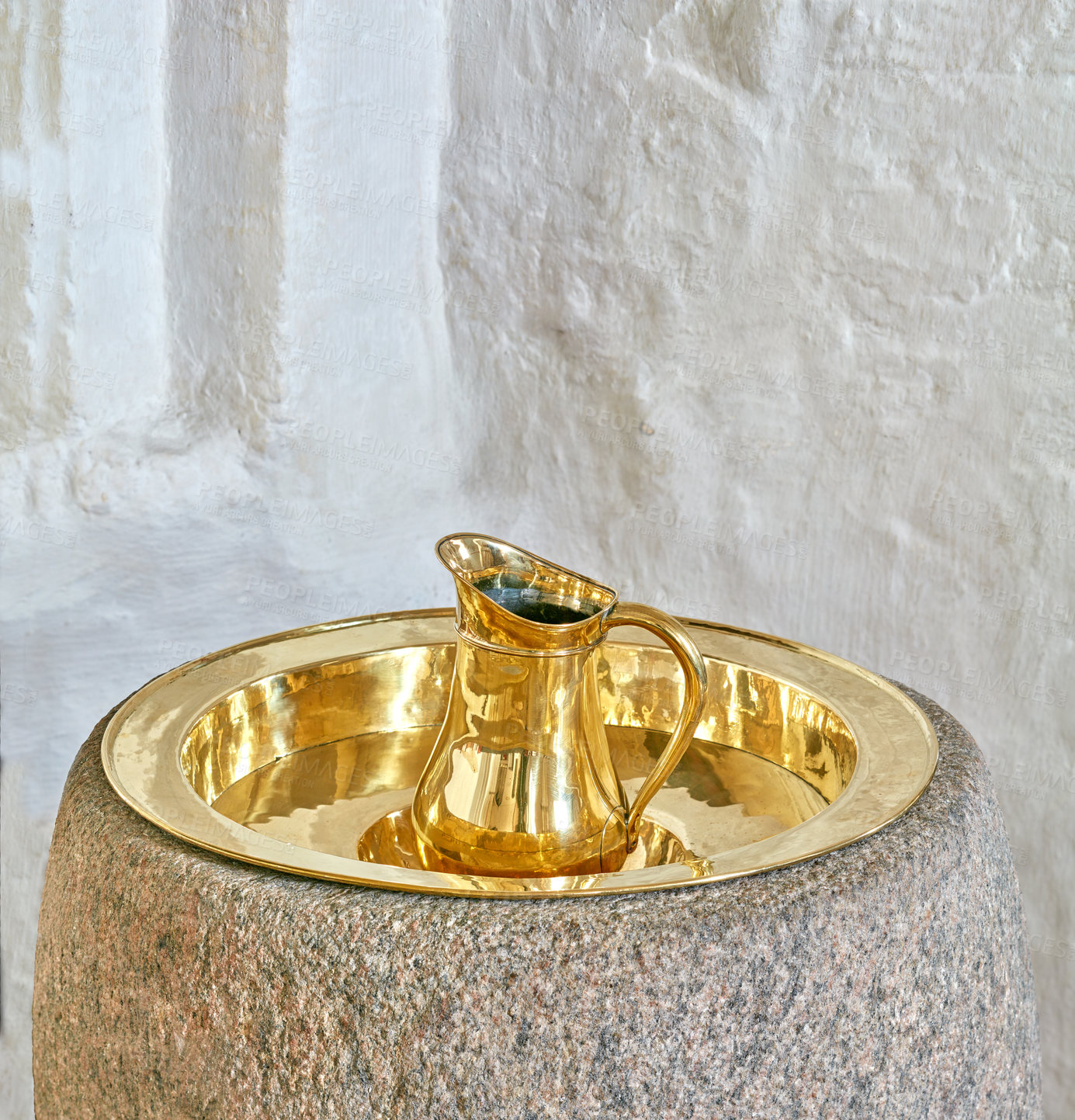 Buy stock photo Closeup of one gold and brass baptism jug on a tray in a church. A sacred pitcher used for pouring water at christening ceremonies. An antique baptismal font in the Danish National Church in Denmark