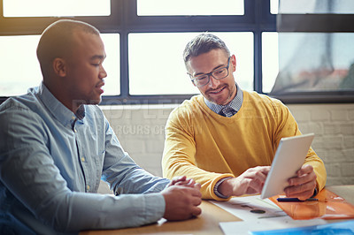 Buy stock photo Shot of two designers working on a digital tablet in an office