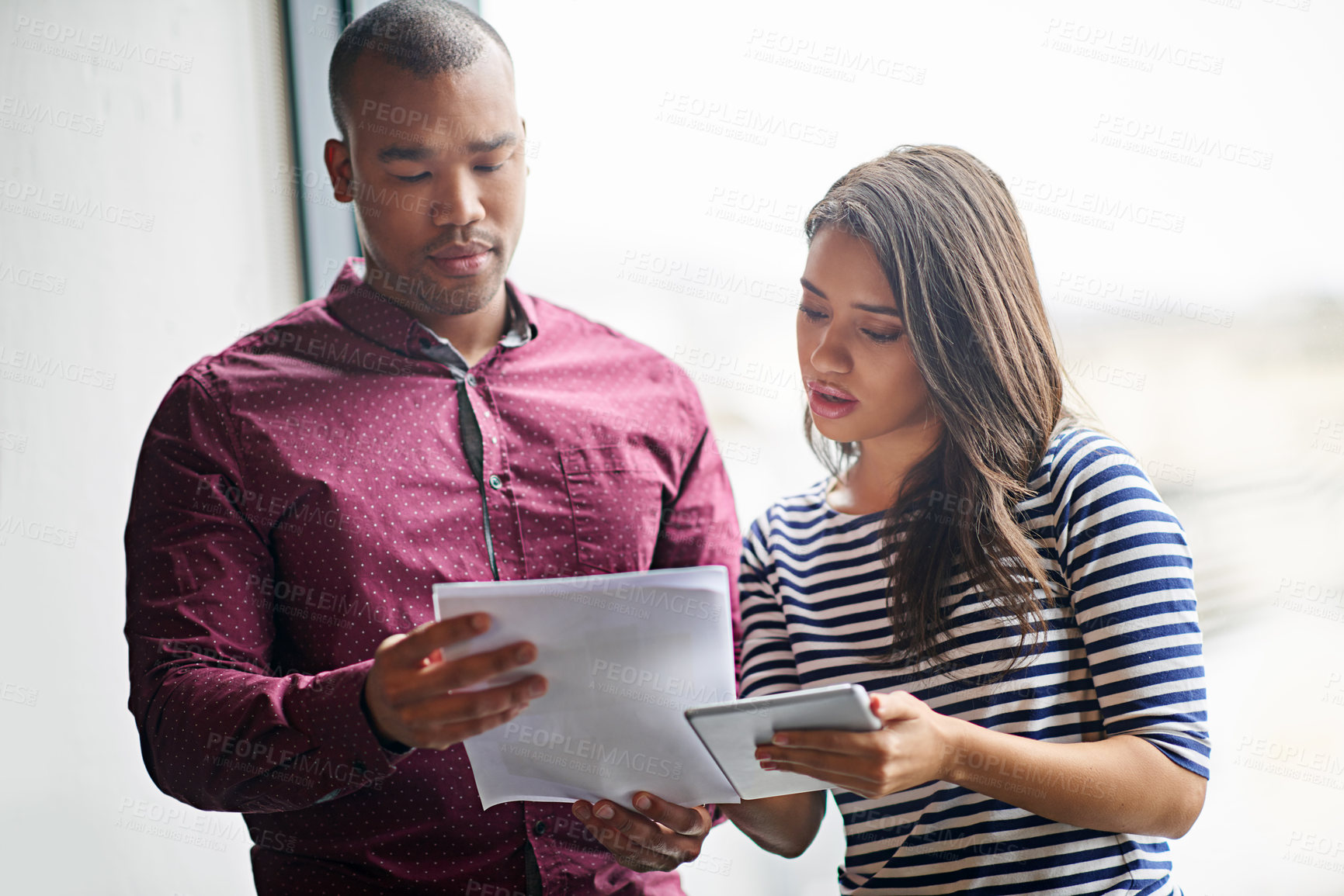 Buy stock photo Colleagues having a discussion while looking at paperwork and holding a digital tablet